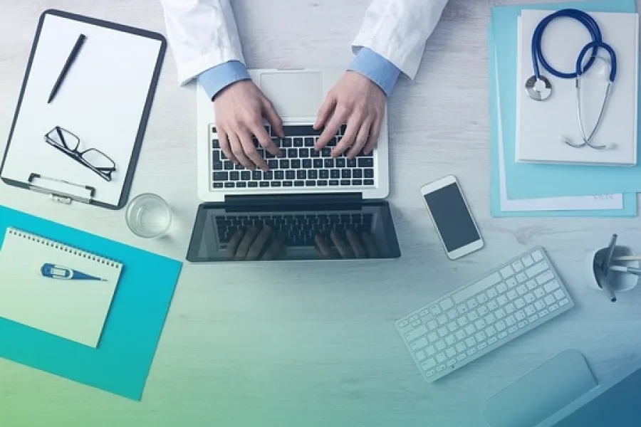 A clinician working at a desk with a stethoscope and notes